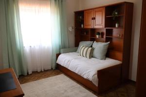 a bed in a room with a shelf and a window at Terras da Planície in Ferreira do Alentejo