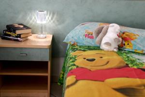 un letto con un piumone di Winnie the Pooh e animali di peluche sopra di Residence ONDA BLU 2 a Cervia