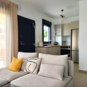 a living room with a white couch with yellow pillows at Bellerive Villas in Kriopigi