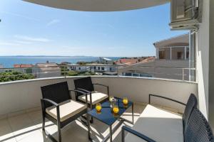 a patio with two chairs and a table on a balcony at Apartments Villa Mirela in Petrcane