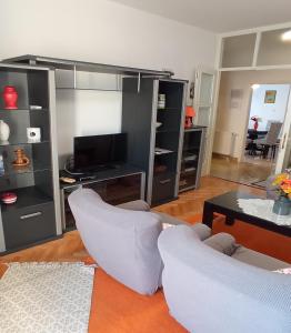 a living room with two white chairs and a television at Apartments Sunag in Šibenik