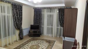 a living room with curtains and a tv and a rug at 12 Месяцев in Cholpon-Ata