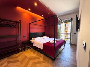 ein Schlafzimmer mit Himmelbett und roter Wand in der Unterkunft CEFALUX - Apartments Collection in Cefalú