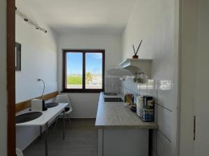 a white kitchen with a sink and a counter at Room Novakovic in Biograd na Moru