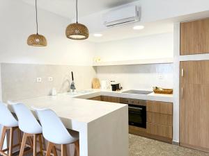 a kitchen with a white counter top and wooden cabinets at Sakellis Home 2- Steps to Beach & Town in Kardamaina
