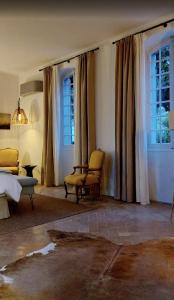 a bedroom with a bed and two chairs and windows at Le Mûrier in Vaison-la-Romaine +123 photos