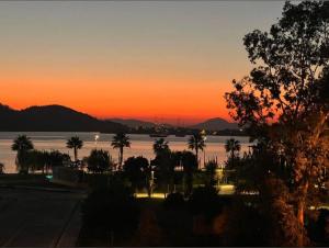 费特希耶Poblos Room的棕榈树的海水上日落