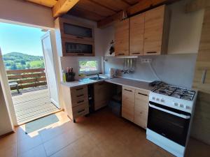 a kitchen with a stove and a sink and a window at Chata Hulina in Moderštôlňa