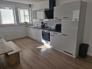 a kitchen with white appliances and a wooden floor at Gasthaus Sonne 3 in Braunsbach