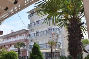 a building with a palm tree in front of it at Giannis Hotel in Paralia Katerinis