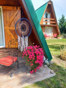 una sedia e dei fiori sul portico di una baita di Cabañas Sueño Serrano a Saldungaray