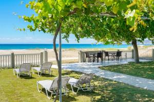 波托什Olivento Beach Front Suites的海滩附近的树下桌椅