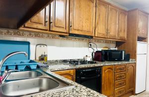 a kitchen with wooden cabinets and a sink and a stove at Sweet Home in Miranda do Douro