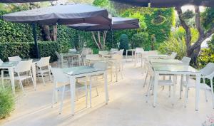 a group of tables and chairs with an umbrella at Hôtel Beau Site - Cap d'Antibes in Antibes