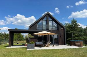 a modern house with a large roof with an umbrella at Nowoczesna stodoła z balią na Mazurach in Trelkowo
