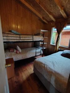 two bunk beds in a room with wooden walls at Cabaña El Ulmo in Puerto Rico