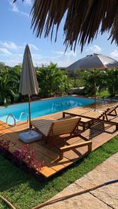 a deck with chairs and an umbrella next to a pool at Vila Orun Pousada in Barreirinhas
