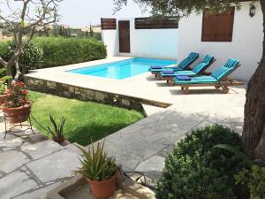 a pool with blue lounge chairs next to a house at Cobblers in Maroni