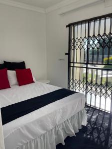 a bedroom with a white bed with red pillows at Kwa Mmaloapi Guest House in Rustenburg