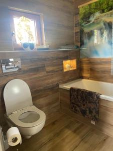 a bathroom with a toilet and a bath tub at Mazurski Reset in Wilnowo