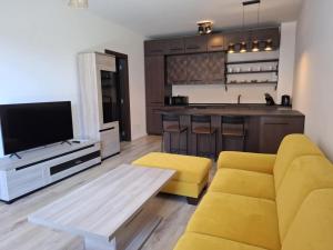 ニトラにあるORBIS Premium apartmentのリビングルーム(黄色のソファ付)、キッチンが備わります。