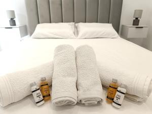 un lit avec des serviettes blanches et des bouteilles de miel dans l'établissement Sueno de luz Corfu, à Áfra