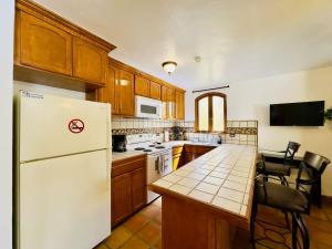a kitchen with a white refrigerator and a table with chairs at Puerto Nuevo Surf Casita del Arte 1BR with pool in Raulis