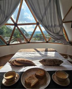 a bed with a table with bread and two cups of coffee at Estância Janela Natural in Lambari