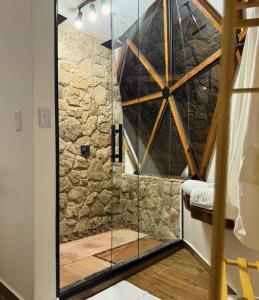 a glass shower in a room with a stone wall at Estância Janela Natural in Lambari