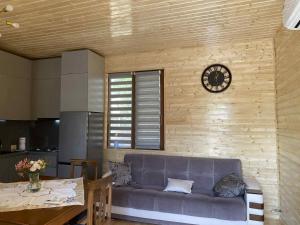 a living room with a couch and a clock on the wall at Mana Home777 in Zugdidi
