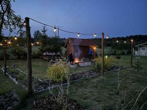 a small cabin in a yard at night with lights at Wczasy Pod Sosnami domek z kominkiem in Krutyń +9 photos