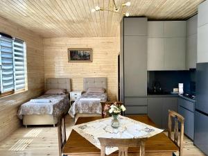 a room with two beds and a table and a kitchen at Mana Home777 in Zugdidi