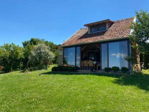a house with large glass windows on a green lawn at Kuća Čerevićki Vidikovac in Čerević
