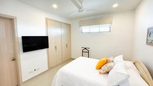 科韦尼亚斯Magico Apartamento Frente al Mar 3 Habitaciones AR12的一间带床和平板电视的白色卧室