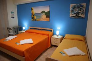 two beds in a bedroom with orange sheets at Casa Vacanze Sicilia Tirrena in Finale