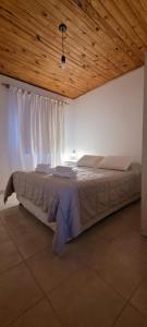 a bedroom with a large bed with a wooden ceiling at La hogareña in El Calafate