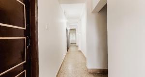 a hallway with white walls and a wooden door at Super Hotel O Sushma Lodge in Manipala