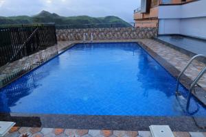 a large swimming pool with blue water in a building at Himasailam Pool Resort Vagamon in Vagamon