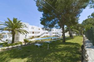 a park with benches and trees in front of a building at Apartamentos Ferrera Pins in Cala Ferrera