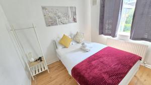 a bedroom with a white bed with a pink blanket at Canary wharf cottage in London +3 photos