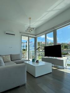 ein Wohnzimmer mit einem weißen Sofa und einem Fernseher in der Unterkunft Anemoni Beach Hotel in Skiathos-Stadt