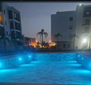 サレにあるMarina Salé Luxury Apartment, Sea Viewのヤシの木や建物が並ぶ夜のスイミングプール
