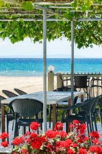 a table and chairs at the beach with red flowers at Opalium Beach Front Suites in Potos