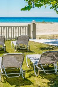 three lawn chairs sitting on the grass near the beach at Opalium Beach Front Suites in Potos