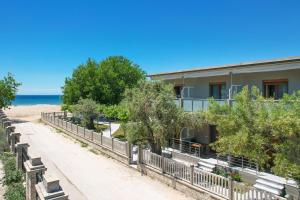 a building on the beach with trees and benches at Opalium Beach Front Suites in Potos