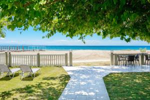 a walkway to the beach with chairs and a table at Opalium Beach Front Suites in Potos