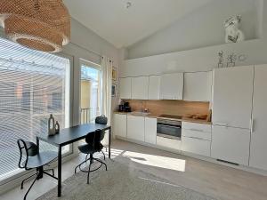 a kitchen with white cabinets and a black table at Kiva Yksiö omalla autopaikalla Bassenkuja Kauklahti Espoo in Espoo