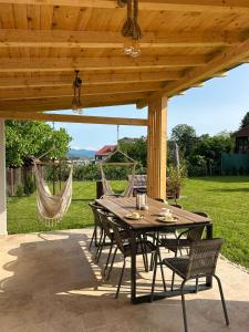 a table and chairs under a wooden pergola at Vila San Nicoara in Curtea de Argeş