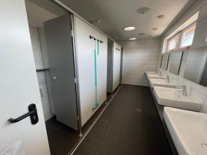 a bathroom with three sinks and a shower at Campingplatz Wohnwagen mit Vorzelt in Affing