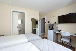 a hotel room with a white bed and a kitchen at Camdene Guesthouse in Cape Town